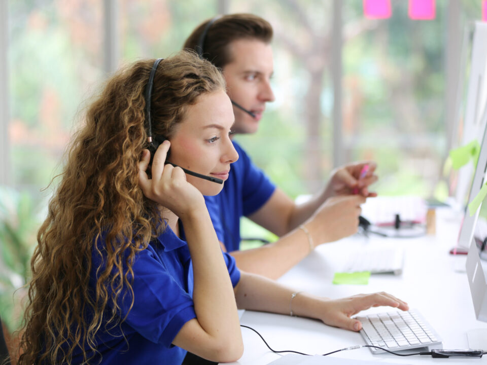 Hotline Support Service. call center operator in headset working with laptop in modern office, looking at computer screen, free space